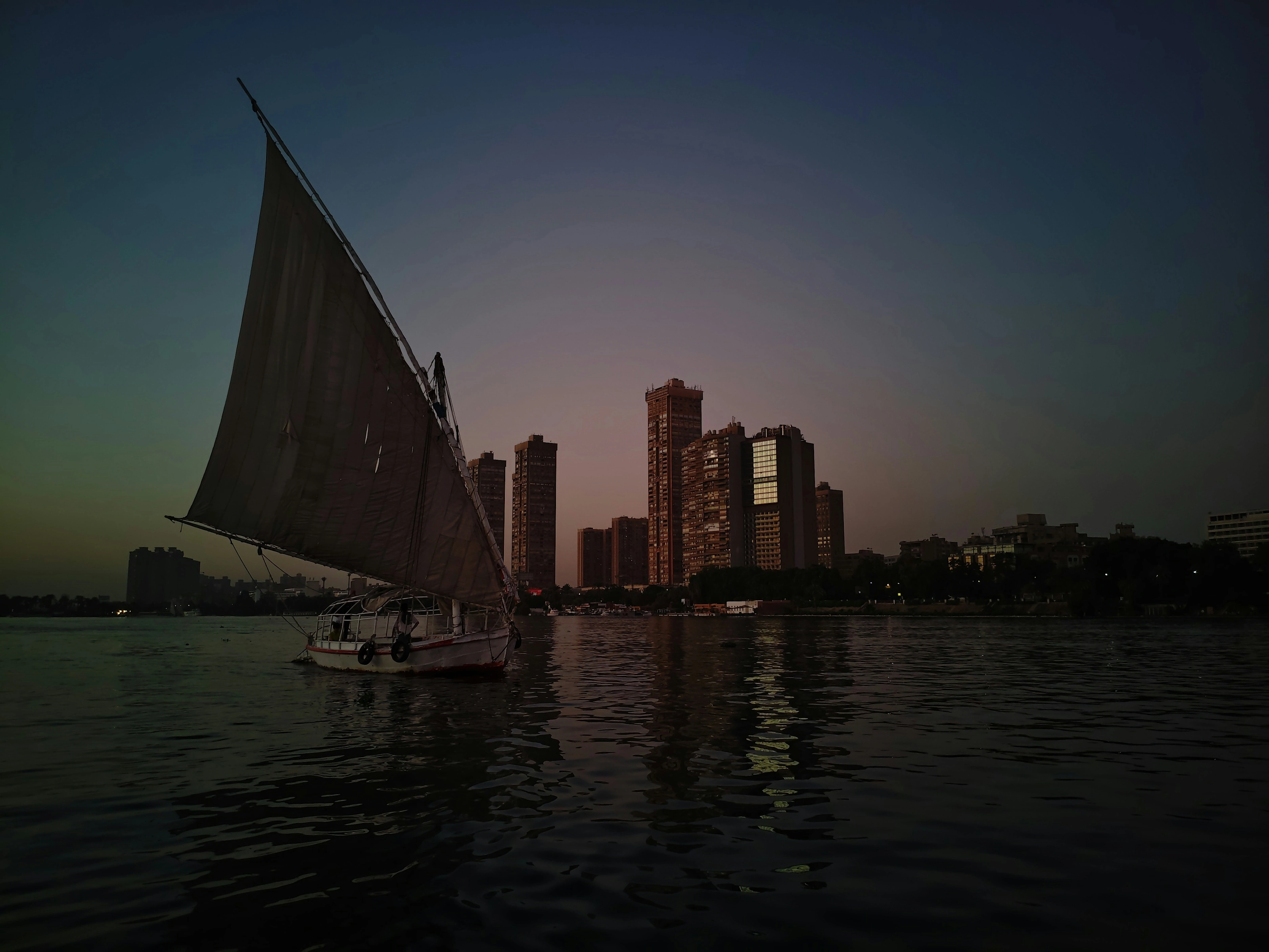 Felucca voguant sur le Nil au coucher du soleil face à la skyline du Caire