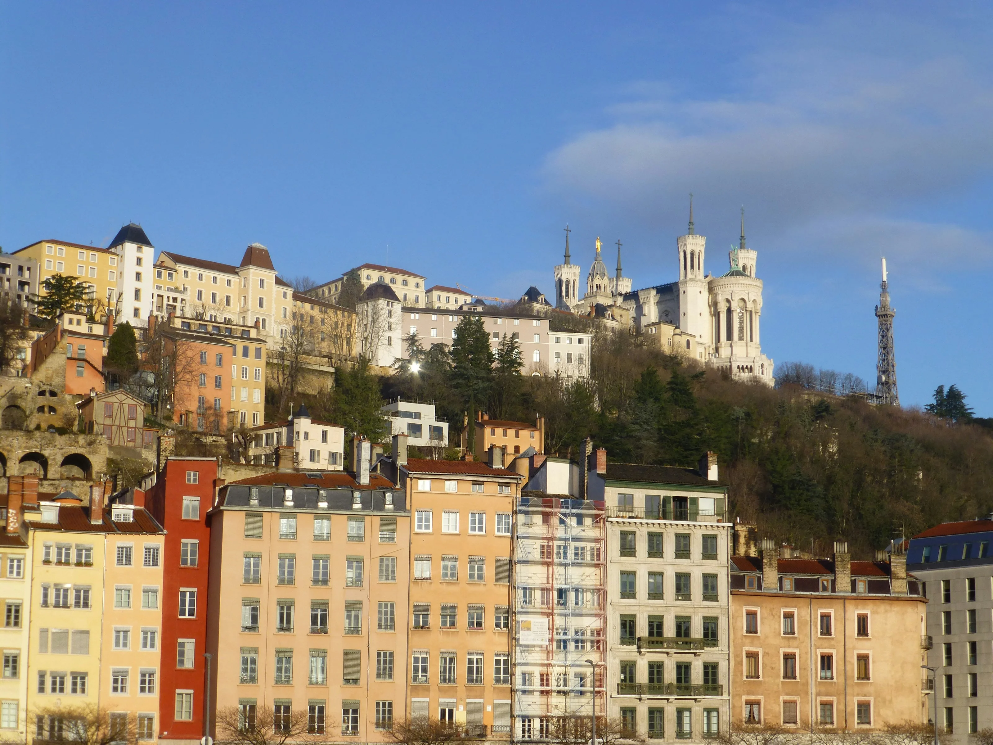 Colorful facades of Vieux Lyon with the Fourvière basilica above, at golden hour