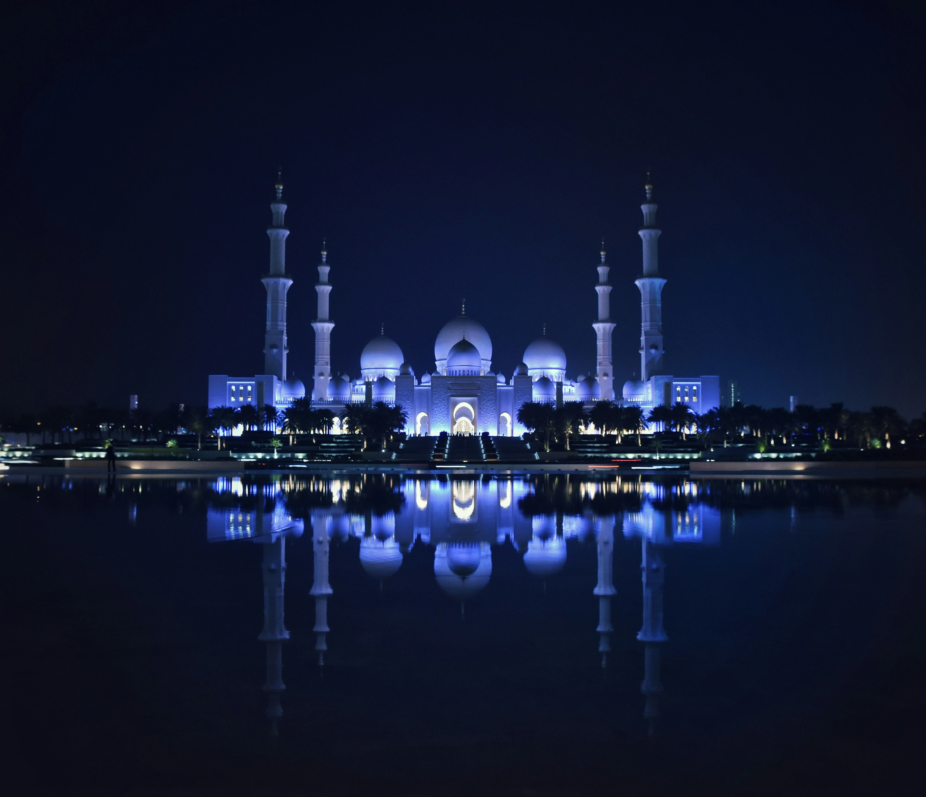 Grande Mosquée Sheikh Zayed illuminée et reflétée dans ses bassins la nuit